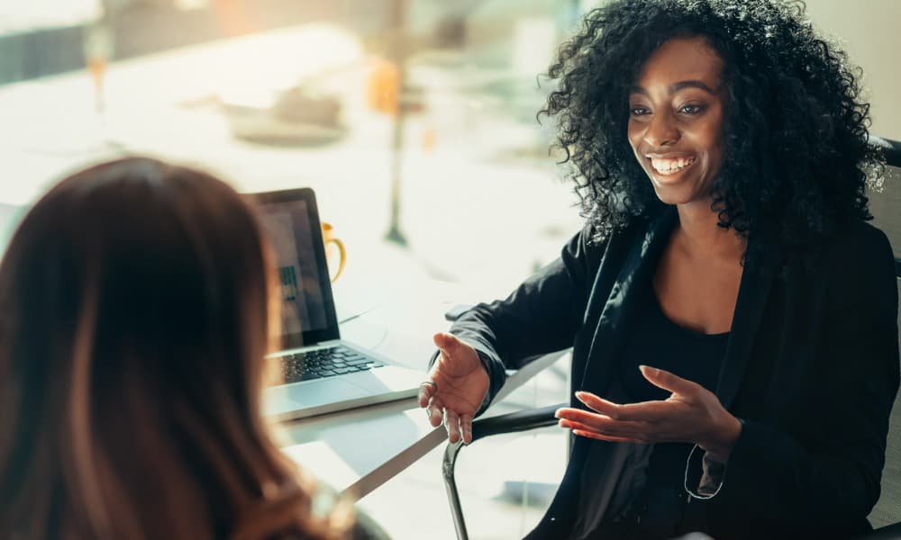 A woman talking to a colleague in an office.