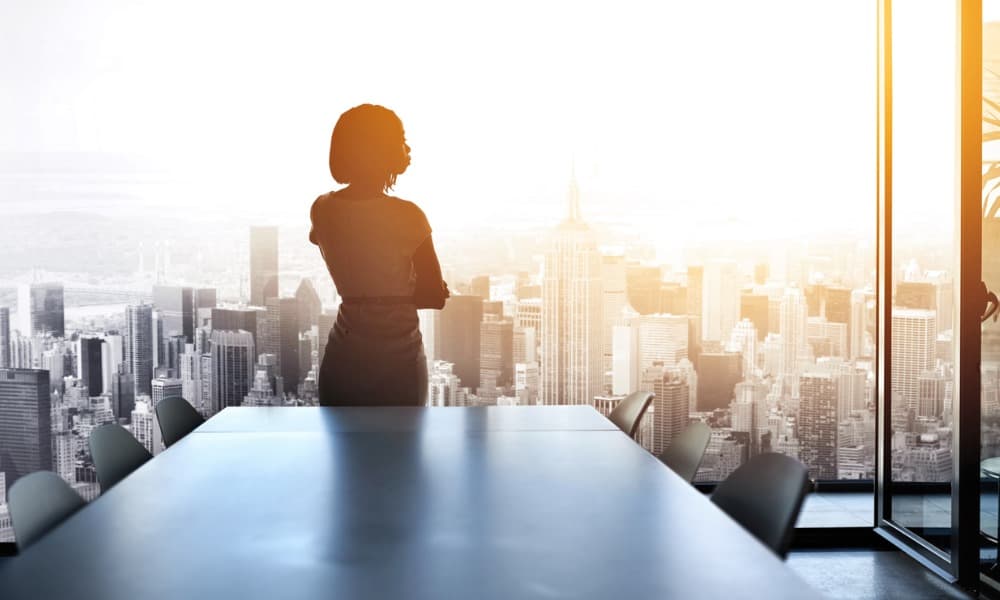 A woman looking out the window of an office building onto a city.